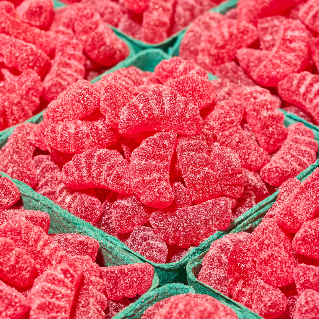 Close-up of red gummy fruit slices in a green tray