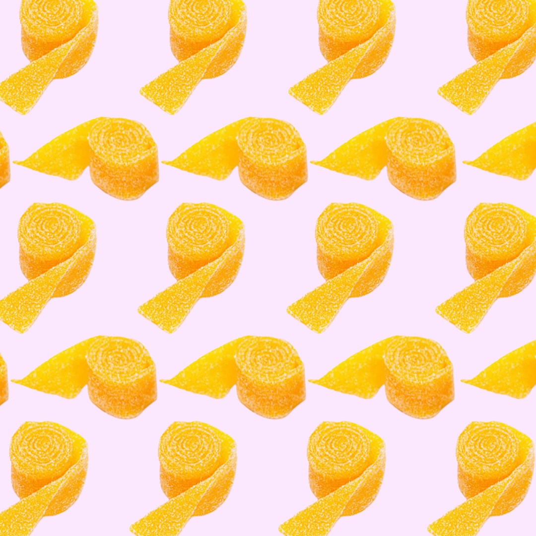 Pattern of yellow mango belt candies from the Netherlands on a pink background