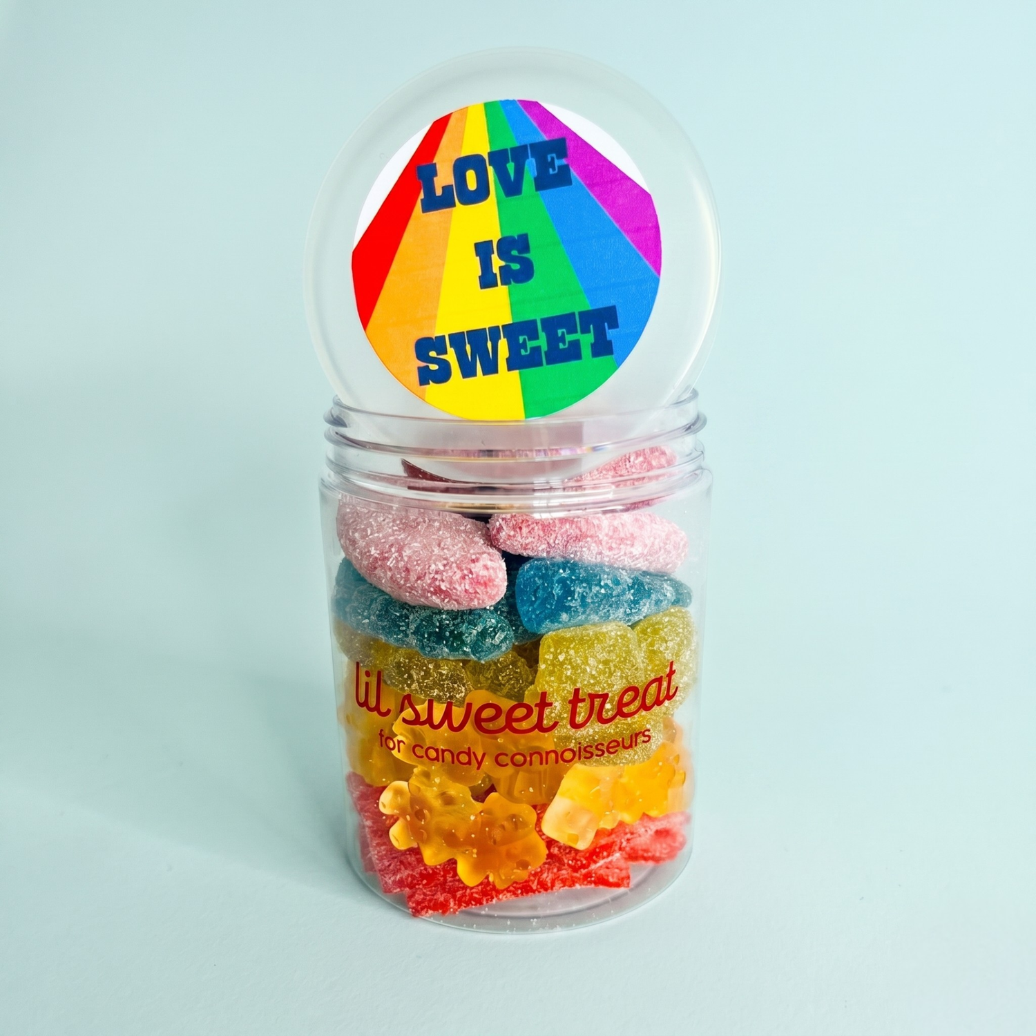 Jar of colorful gummy bears with a rainbow lid labeled 'Love is Sweet' on a light blue background.