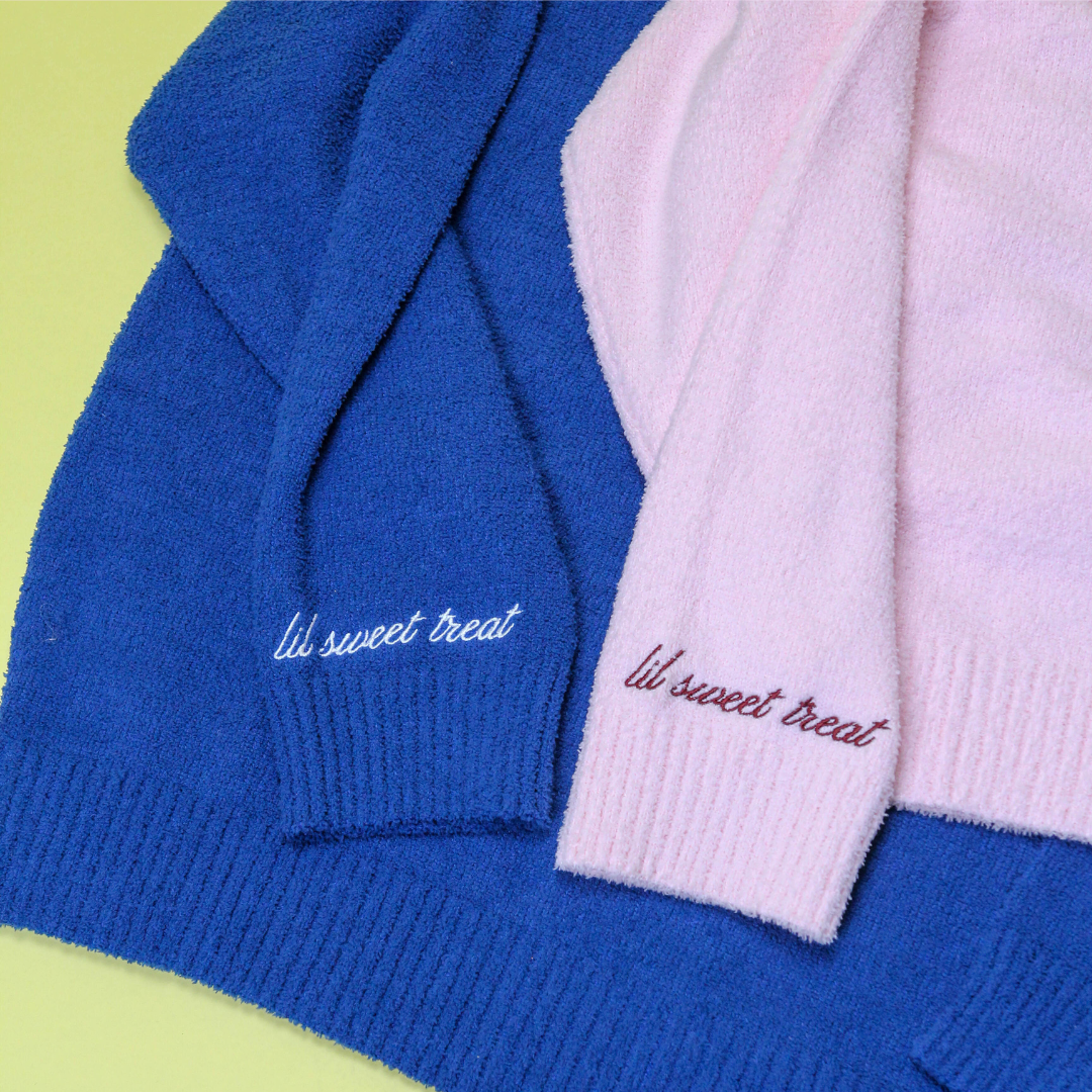Two hoodies, one blue and one pink, with 'lil sweet treat' embroidery on a green background.