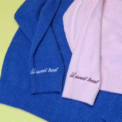 Two hoodies, one blue and one pink, with 'lil sweet treat' embroidery on a green background.