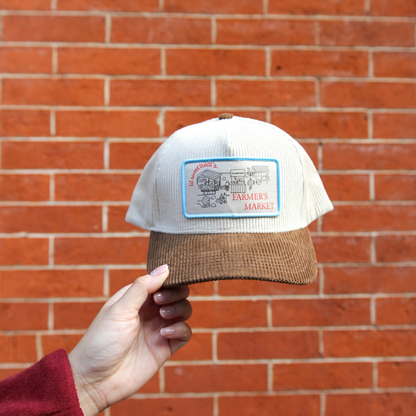 brown and cream corduroy hat with a scene of a farmers market with lil sweet treat logo