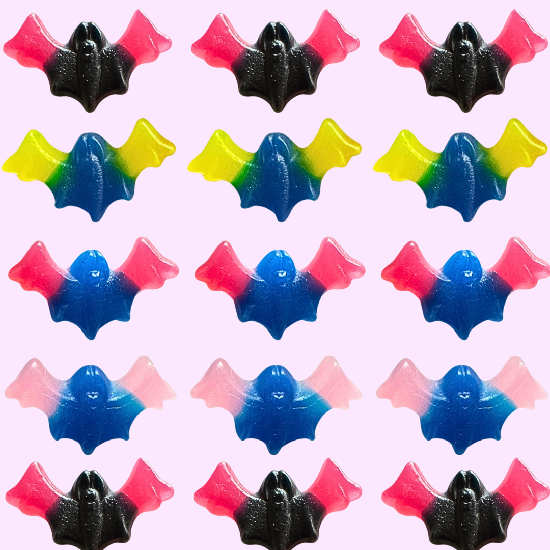 Pattern of colorful bat-shaped gummy candies on a light pink background