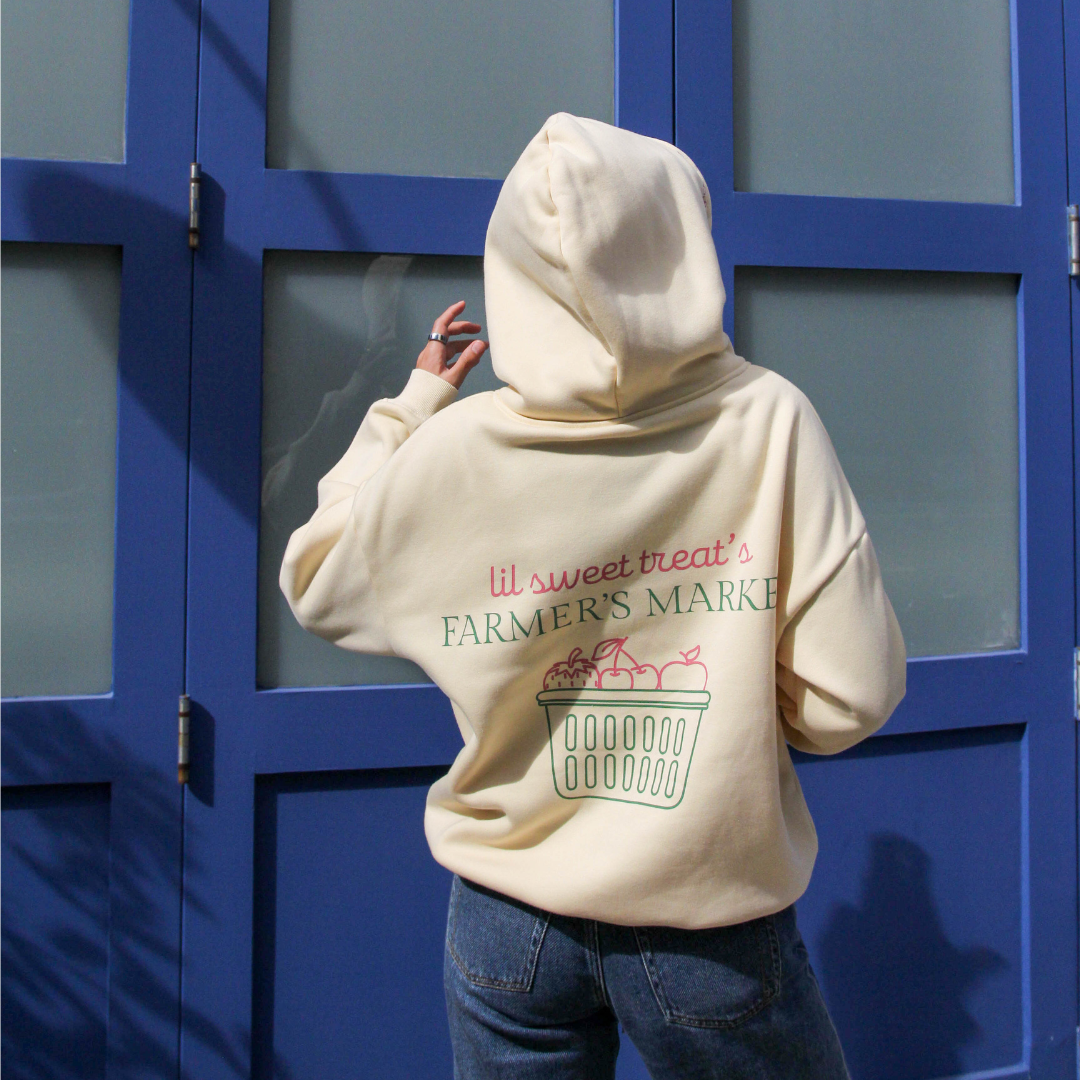 Person wearing a beige hoodie with text and graphics in front of a blue door.