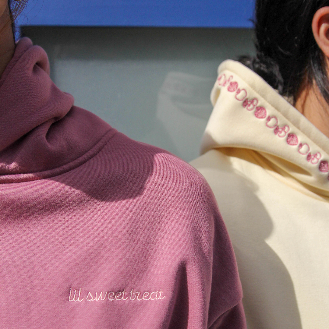 Two people wearing hoodies with visible branding against a blue background