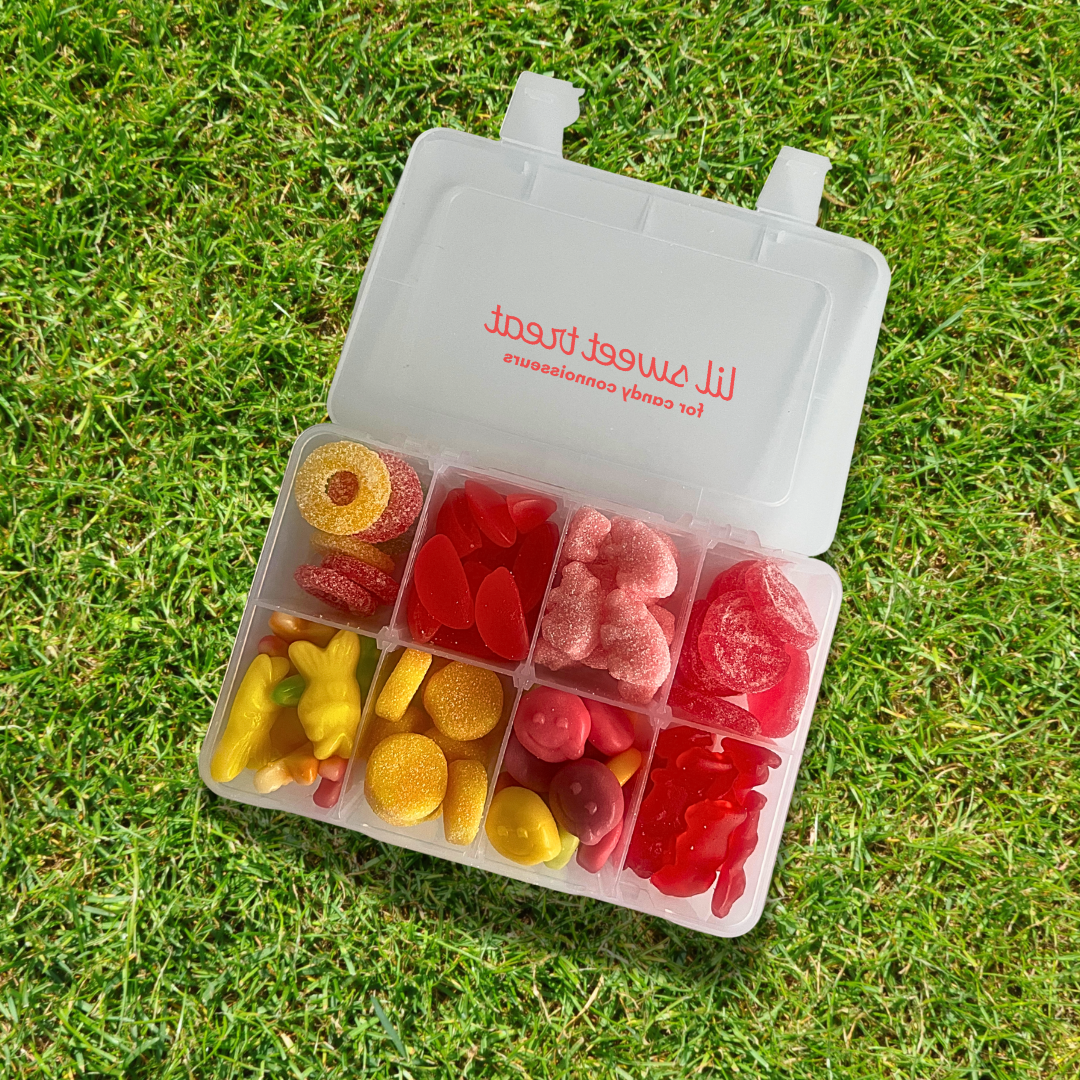 Open container of colorful gummy candies on grass