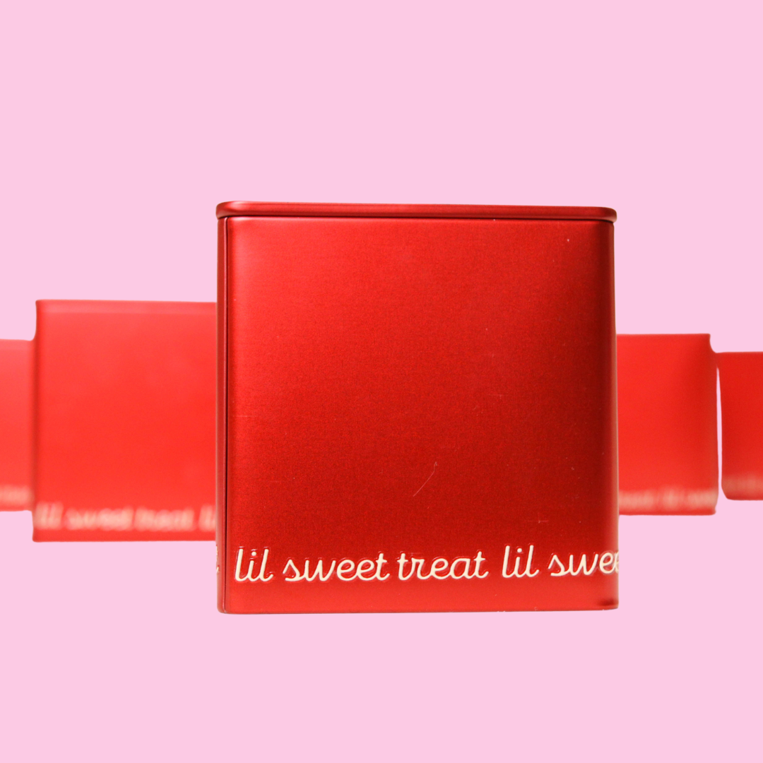 Red tin with 'lil sweet treat' along the bottom on a pink background