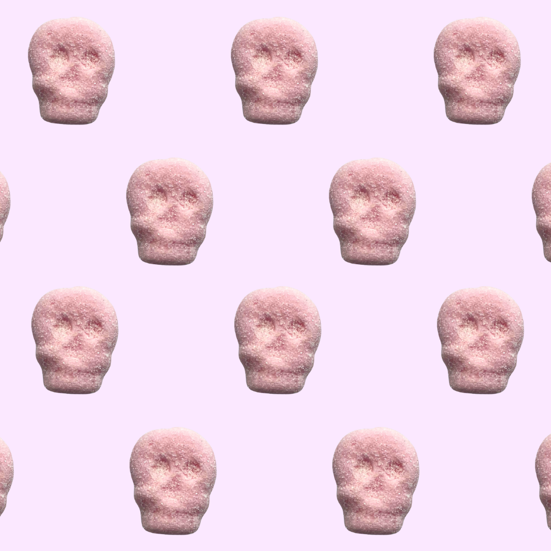 Pattern of pink skull-shaped gummies on a pink background