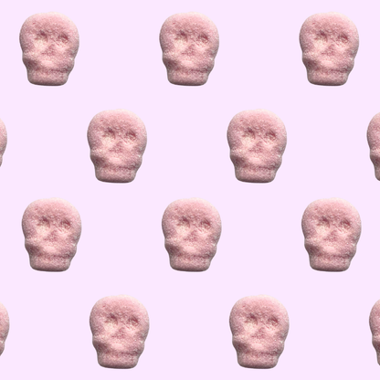 Pattern of pink skull-shaped gummies on a pink background