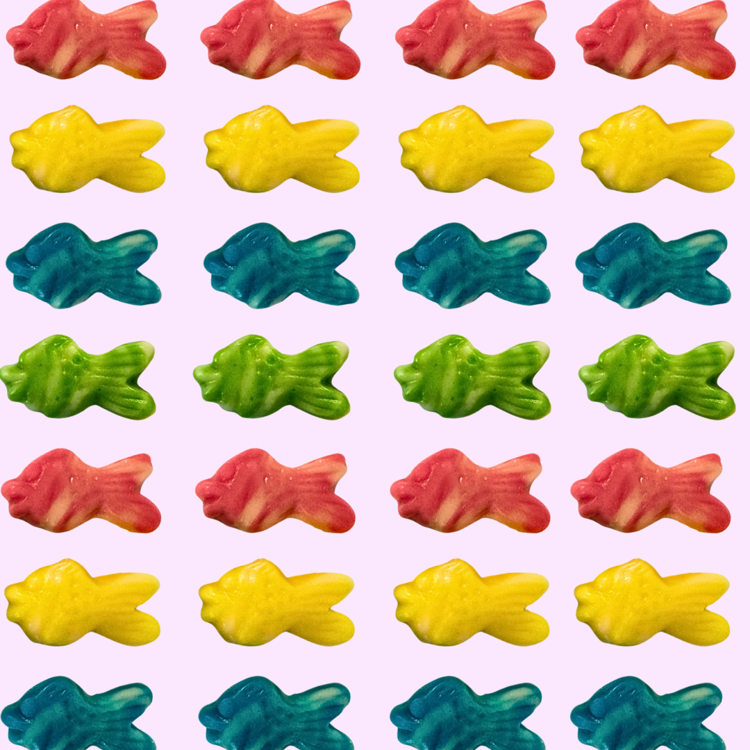 Pattern of colorful fish-shaped gummy candies on a pink background